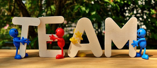 The Letter TEAM spelled out with 4 little plastic men holding each letter. 